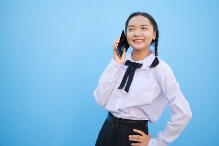 Student young girl useing smart phone on blue background.の写真素材