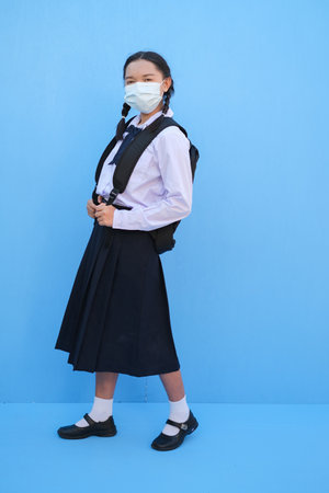 School girl wear mask on blue background,Back to school.の写真素材