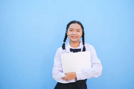School girl holding billboard on blue background.の写真素材