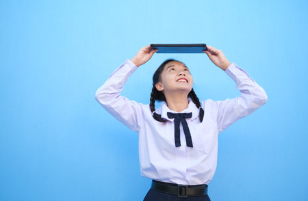 School girl holding tablet on blue background.の写真素材