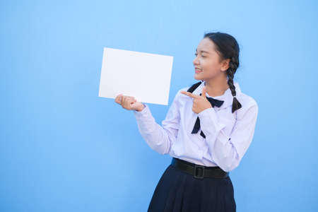 School girl holding billboard on blue background.の写真素材