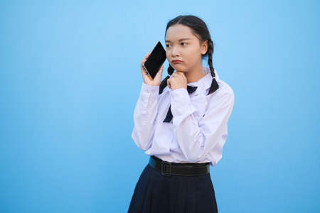 Student young girl useing smart phone on blue background.の写真素材