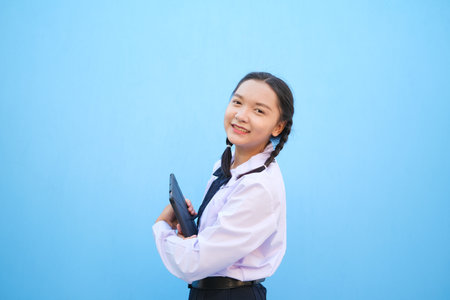 School girl holding tablet on blue background.の写真素材