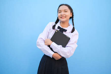 School girl holding tablet on blue background.の写真素材