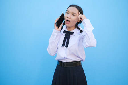 Student young girl useing smart phone on blue background.の写真素材