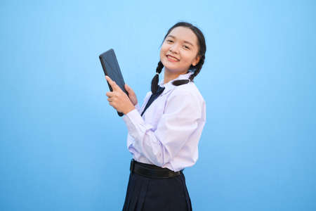 School girl holding tablet on blue background.の写真素材