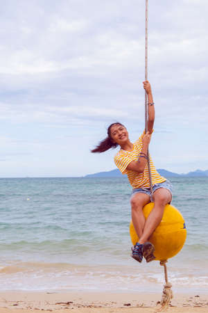 Happy girl playing ball swing on the beach, Kohmak Thailand.の写真素材