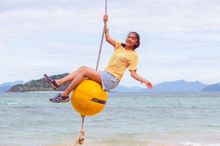Happy girl playing ball swing on the beach, Kohmak Thailand.の写真素材