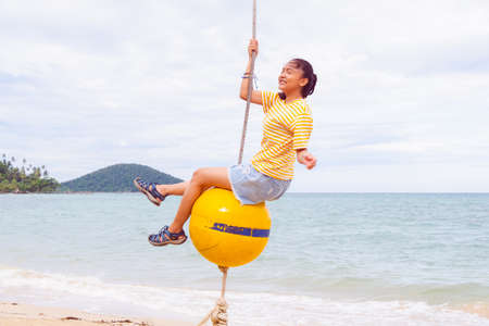 Happy girl playing ball swing on the beach, Kohmak Thailand.の写真素材