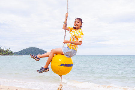 Happy girl playing ball swing on the beach, Kohmak Thailand.