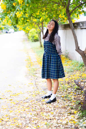 Young girl standing under yellow floawer tree.の写真素材