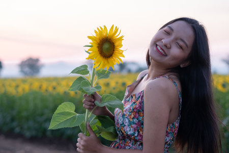 Closeup picture beautiful young girl with sunflower at flower filed in the morning.の写真素材