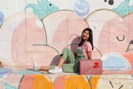 The cheerful girl wearing party hat with gift box sitting on colorful background.の写真素材