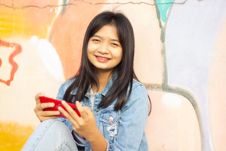 Young girl playing game on smartphone sitting on colorful background.の写真素材