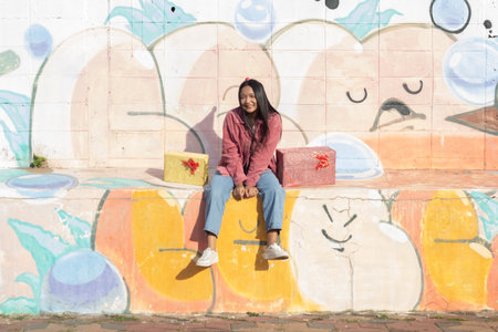 The cheerful girl wearing party hat with gift box sitting on colorful background.の写真素材