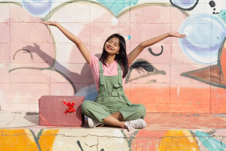 The cheerful girl wearing party hat with gift box sitting on colorful background.の写真素材