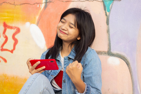Young girl playing game on smartphone sitting on colorful background.の写真素材