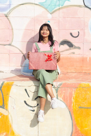The cheerful girl wearing party hat with gift box sitting on colorful background.の写真素材