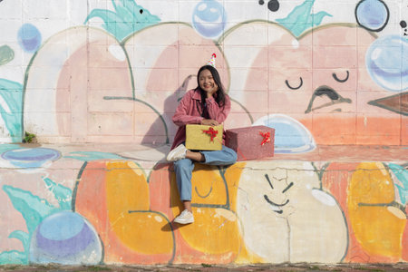 The cheerful girl wearing party hat with gift box sitting on colorful background.の写真素材