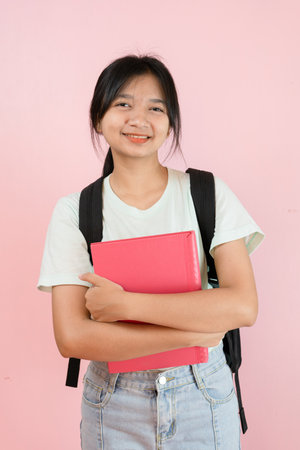 Happy student young girl hold pink book and backpack on pink background.の写真素材