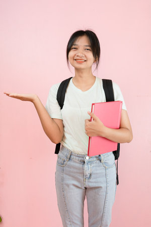 Happy student young girl hold pink book and backpack on pink background.の写真素材