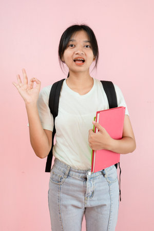Happy student young girl hold pink book and backpack on pink background.の写真素材