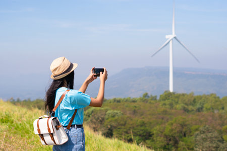 Young girl standing on the mountain taking beautiful landscape view and the Wind Turbine at Khao Yai Thieng Electric Wind Turbine Thailand.の写真素材