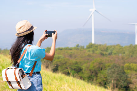Young girl standing on the mountain taking beautiful landscape view and the Wind Turbine at Khao Yai Thieng Electric Wind Turbine Thailand.の写真素材