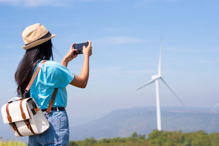 Young girl standing on the mountain taking beautiful landscape view and the Wind Turbine at Khao Yai Thieng Electric Wind Turbine Thailand.の写真素材