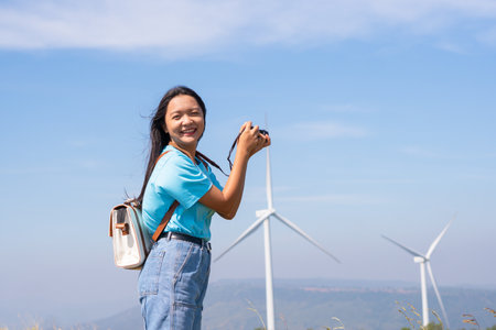 Traveler girl taking photo beautiful landscape view and windmill at Khao Yai Thieng Electric Wind Turbine Thailand.の写真素材
