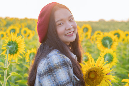 Happy young girl standing in the sunflowers field on vacation time.の写真素材