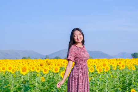 Beautiful young girl standing in the sunflowers field. Vacation time.の写真素材