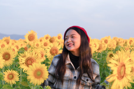 Happy young girl standing in the sunflowers field on vacation time.の写真素材