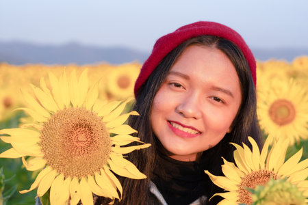 Happy young girl standing in the sunflowers field on vacation time.の写真素材