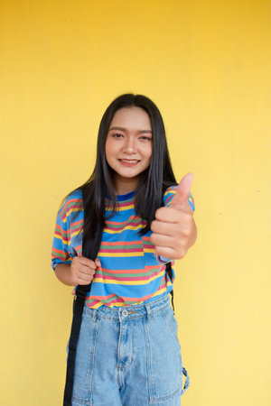 Happy young girl on yellow background, student girl.の写真素材