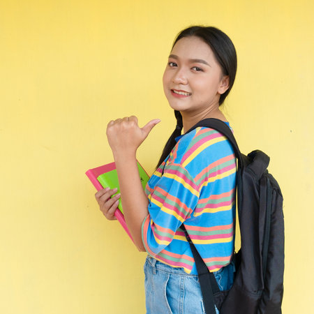Student girl hold book and smiling on yellow background.の写真素材