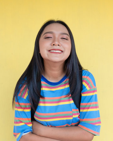 Happy young girl on yellow background, student girl.の写真素材
