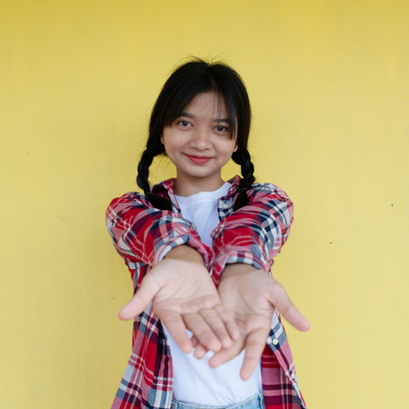 Happy young girl on yellow background, student girl.の写真素材