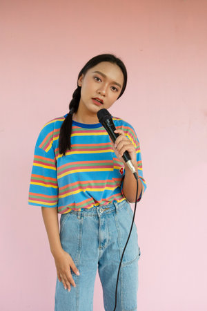The girl standing and singing music on pink background.の写真素材
