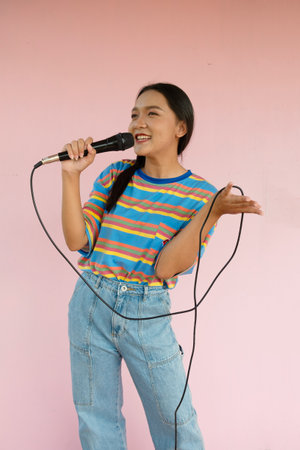 The girl standing and singing music on pink background.の写真素材