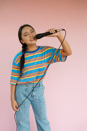 The girl standing and singing music on pink background.の写真素材