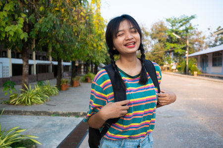 Student young girl hold book and backpack standing at school.の写真素材