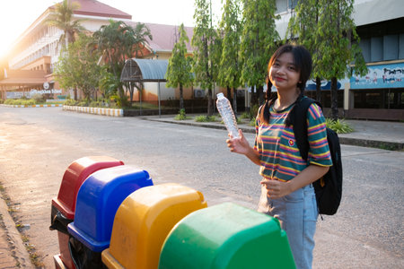 Students put plastic bottles in the trash at school.の写真素材