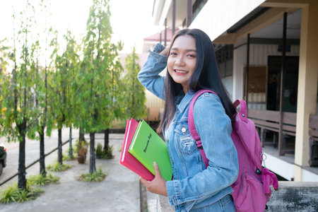 Shool girl hold book with backpak standing at campus.の写真素材