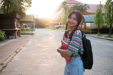 Happy young girl hold book with backpack walking at school.の写真素材