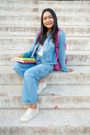 School girl Smiling and sitting on stair hold book at school.の写真素材