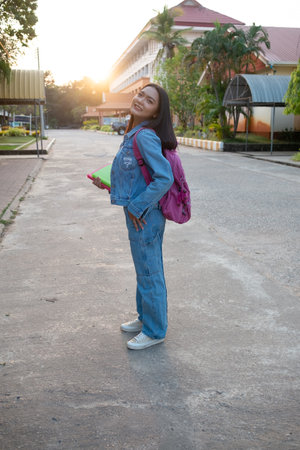 Happy young girl hold book with backpack walking at school.の写真素材