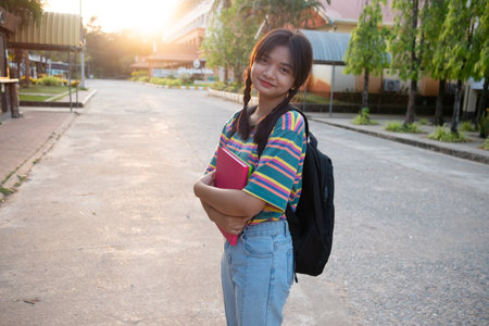 Happy young girl hold book with backpack walking at school.の写真素材