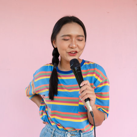 The girl standing and singing music on pink background.の写真素材