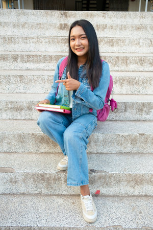 School girl Smiling and sitting on stair hold book at school.の写真素材